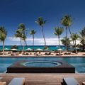 Luxe pool and beach at Kona Village, A Rosewood Resort, with palms and ocean views.