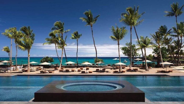 Luxe pool and beach at Kona Village, A Rosewood Resort, with palms and ocean views.