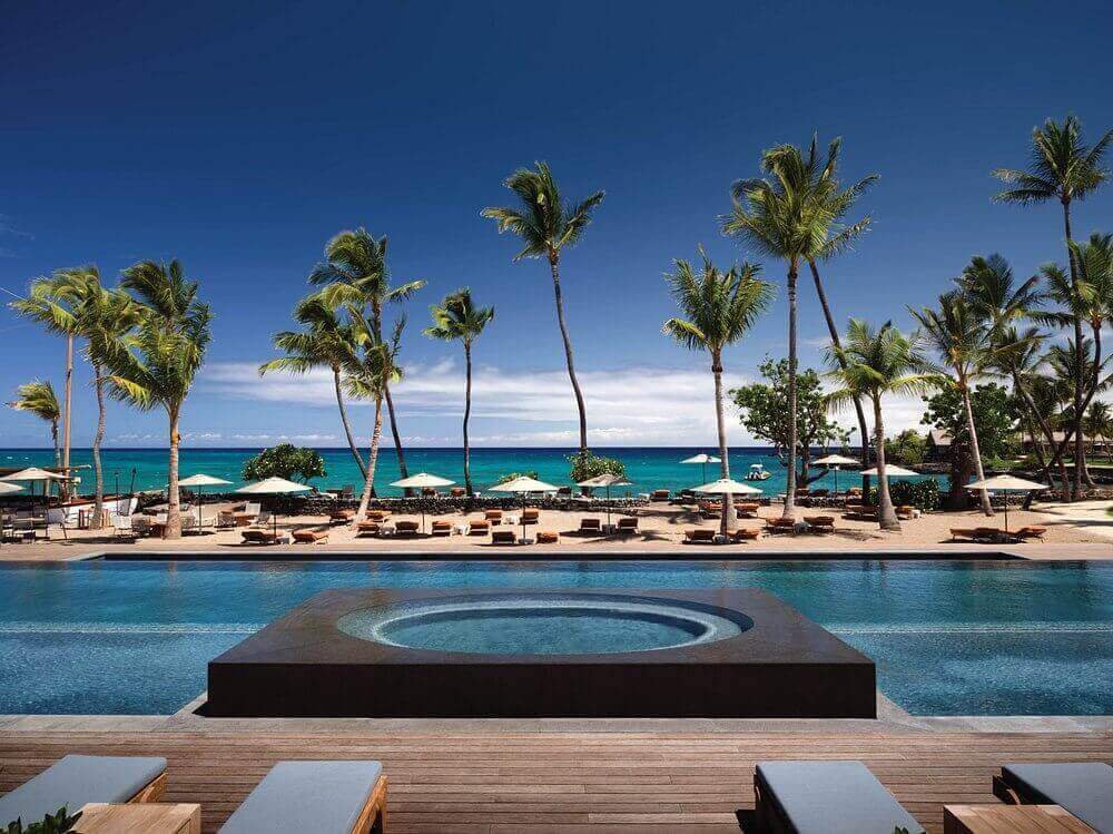 Luxe pool and beach at Kona Village, A Rosewood Resort, with palms and ocean views.