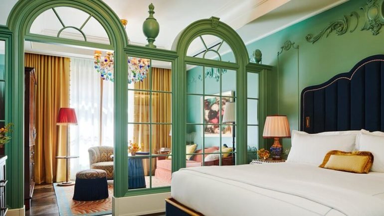 Luxurious The Fifth Avenue Hotel room with elegant decor, cozy bed, and vibrant art.