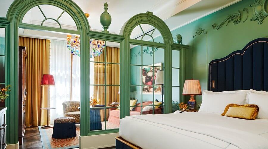 Luxurious The Fifth Avenue Hotel room with elegant decor, cozy bed, and vibrant art.