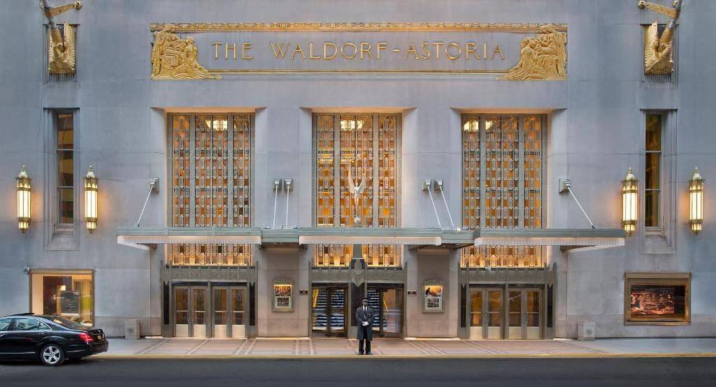Iconic Waldorf Astoria hotel entrance with elegant architecture and doorman.